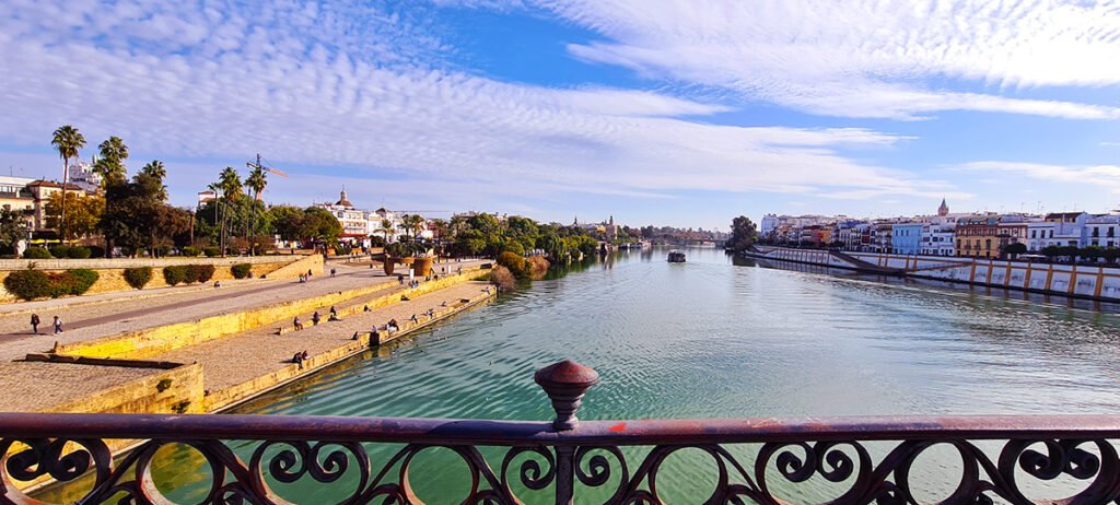 Het water dat midden door Sevilla stroomt, gezien vanaf een brug, met een reflectie van de historische stad en de levendige sfeer.