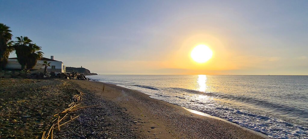 Het strand bij Malaga onder een betoverende ondergaande zon, met de weerspiegeling van de hemel in de kalme Middellandse Zee.