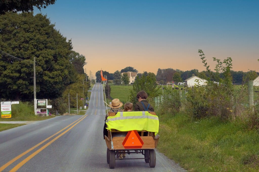 Amish gezin op een paard en wagen op een landelijke weg bij zonsondergang